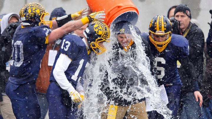 football players pouring water on coach