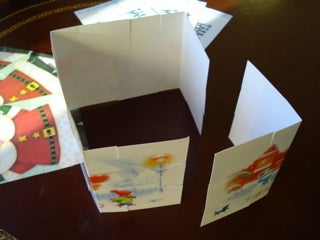 Three holiday cards slotted together, with a fourth ready to finish the tower base.