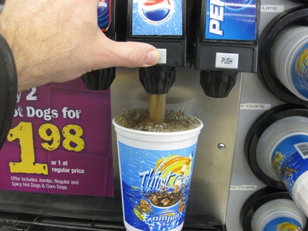 A person dispensing Diet Pepsi from a soda fountain into a plastic cup.