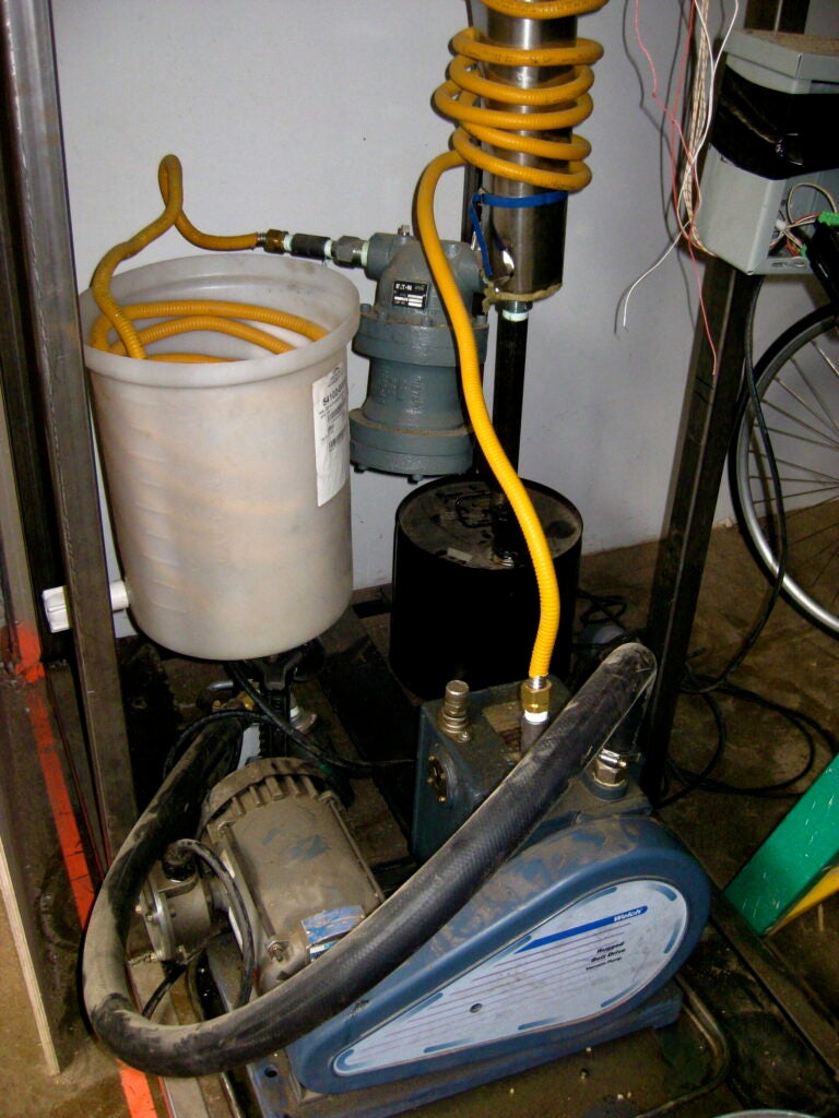 Some gas is left over after the reaction, including methane, carbon monoxide, hydrogen (less than half a percent) and some higher-level hydrocarbons. An explosion-proof pump, in the foreground here, pumps excess gas from the reaction back through the system, and pulls gas through the system, keeping the cycle moving. This particular pump was procured from the old Brooklyn Pfizer factory, which shut down in 2008.