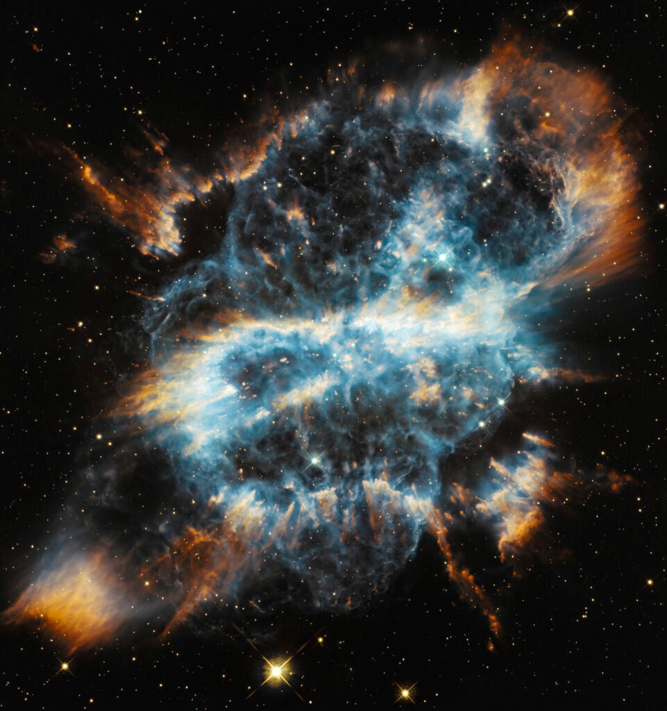 Blue, white, and orange gas with a delicate filamentary structure in space