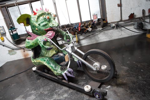 A green hog demon riding a power tool motorcycle.