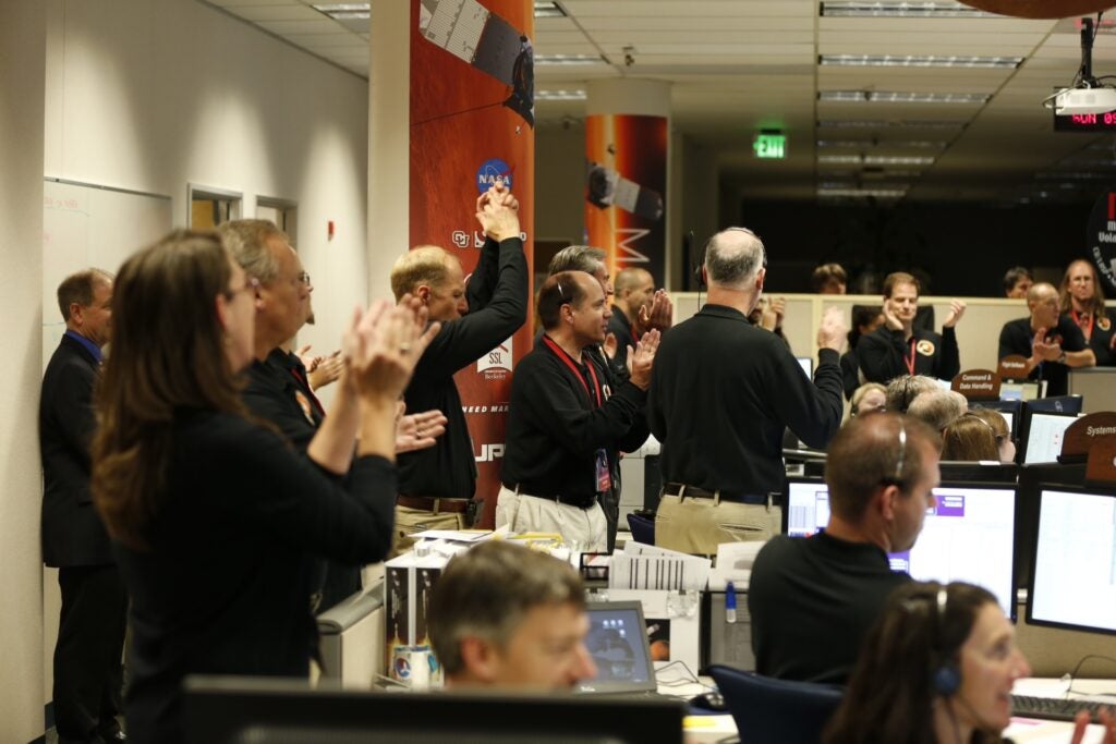 Members of the MAVEN team cheer at the Lockheed Martin operations center in Littleton, Colorado, as the spacecraft successfully entered orbit around Mars on the night of September 21, 2014, after ten months of travel. MAVEN orbits around Mars in an ellipse, flying 93 miles above the planet’s surface at its closest point in orbit, and more than 3,728 miles at its farthest.
