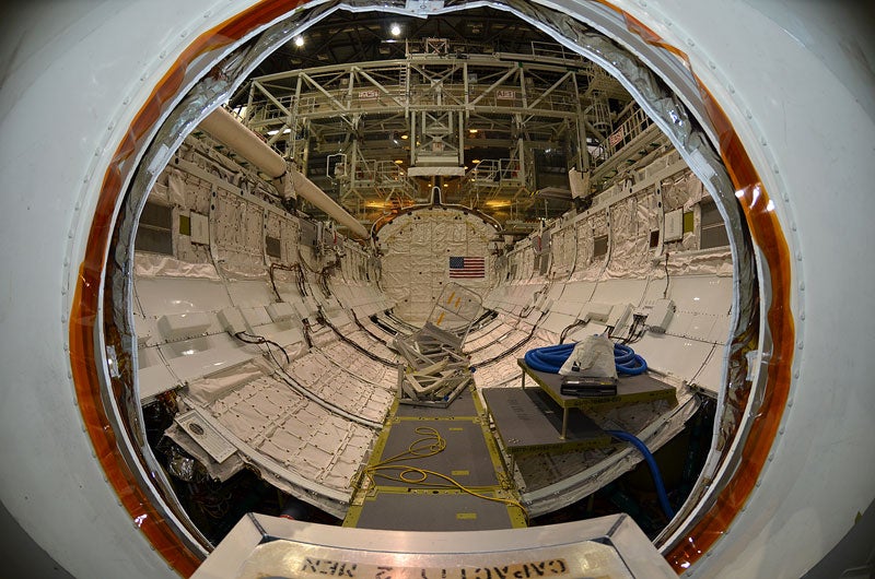 The view through the open airlock hatchway out into Atlantis' 60-foot-long payload bay. Seen mounted to the left sill of the cargo hold, the orbiter boom extension system, which was used in tandem with the robotic arm to inspect Atlantis' heat shield. The Canadarm robotic arm was removed from the left sill the day before these photos were taken to be shipped to Johnson Space Center in Houston for possible future use in space.