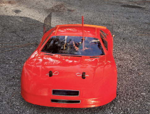 A red remote-control car on a driveway.