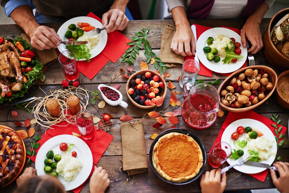 Thanksgiving dinner table from above, colorful plates of food on wood table.