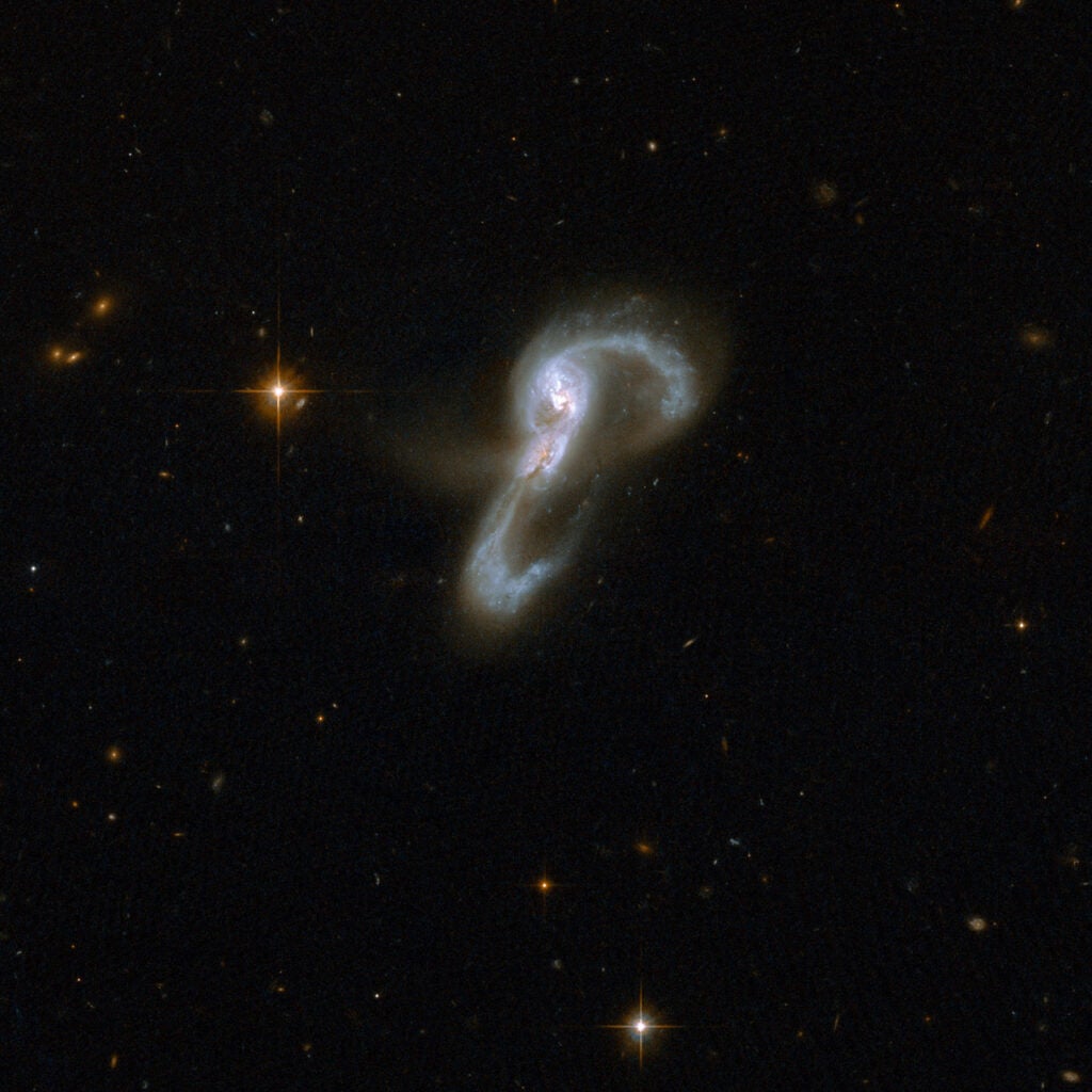 VV 705, or Markarian 848, consists of two galaxies that seem to be embracing each other. Two long, highly curved arms of gas and stars emerge from a central region with two cores. One arm, curving clockwise, stretches to the top of the image where it makes a U-turn and interlocks with the other arm that curves up counter-clockwise from below. The two cores are 16,000 light-years apart. The pair is thought to be midway through a merger. Markarian 848 is located in the constellation of Bootes, the Bear Watcher, and is approximately 550 million light-years away from Earth.