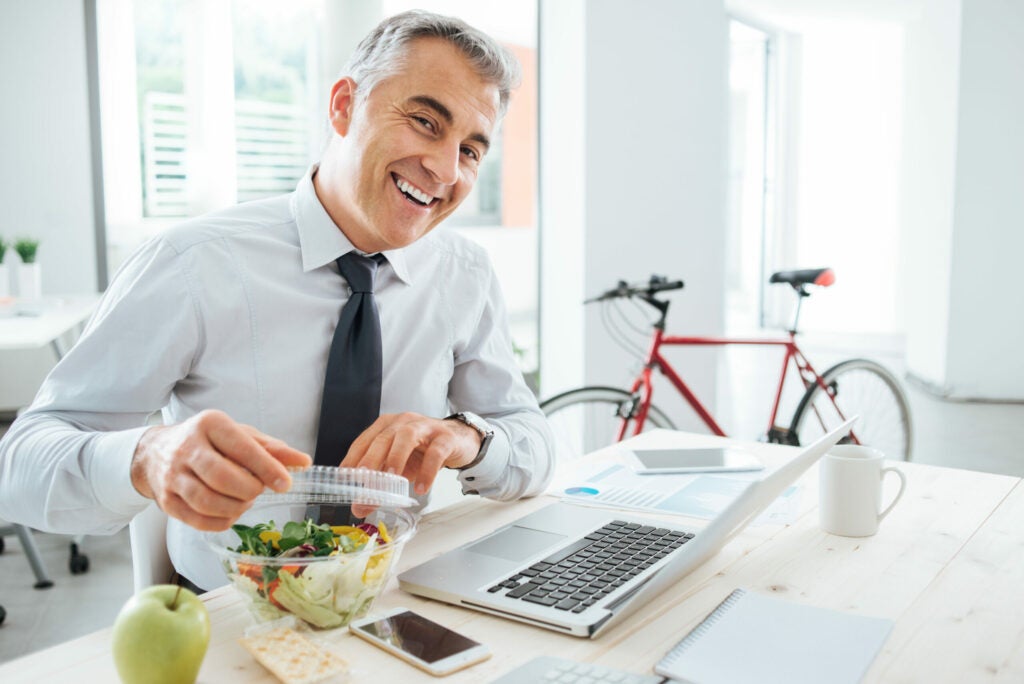 man eating salad with bicycle in the background