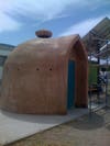 A brown domed structure with a blue door and a vent on the roof.