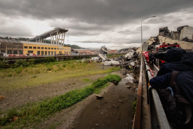 GENOA, LIGURIA - AUGUST 14: Rescuers work to search for survivors after a section of the Morandi motorway bridge collapsed earlier on August 14, 2018 in Genoa, Italy. At least 30 people were killed today when the giant motorway bridge collapsed in north-western Italy, which saw a vast stretch of the A10 freeway tumble on to railway lines. The bridge failure was the country's deadliest in years with the country's deputy transport minister warning the death toll could climb further. (Photo by Awakening/Getty Images)