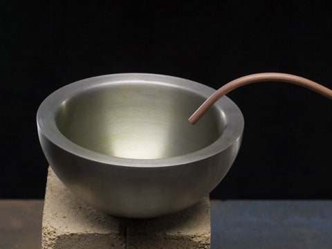 A metal bowl with a copper tube going into it.