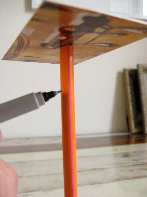 A person making marks on a plastic straw with a fine tip pen.