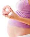 Pregnant woman holding donut