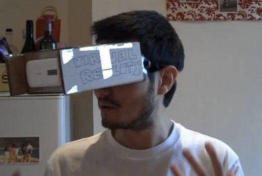 A man wearing DIY augmented reality goggles made out of cardboard and an HTC Magic phone.