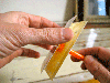 A person sticking two pieces of paper and cardboard together with rubber cement.