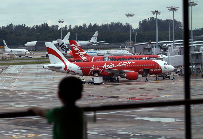 A child looks on at a viewing gallery overlooking AirAsia planes on the tarmac at Changi Airport in Singapore December 29, 2014. The missing AirAsia plane carrying 162 people is presumed to have crashed off the Indonesian coast, an official said on Monday, as countries in the region offered to help Jakarta in the search and recovery effort. The Indonesia AirAsia plane, an Airbus A320-200, disappeared after its pilot failed to get permission to alter course to avoid bad weather during a flight from the Indonesian city of Surabaya to Singapore on Sunday. REUTERS/Edgar Su (SINGAPORE - Tags: TRANSPORT DISASTER) - RTR4JGUT