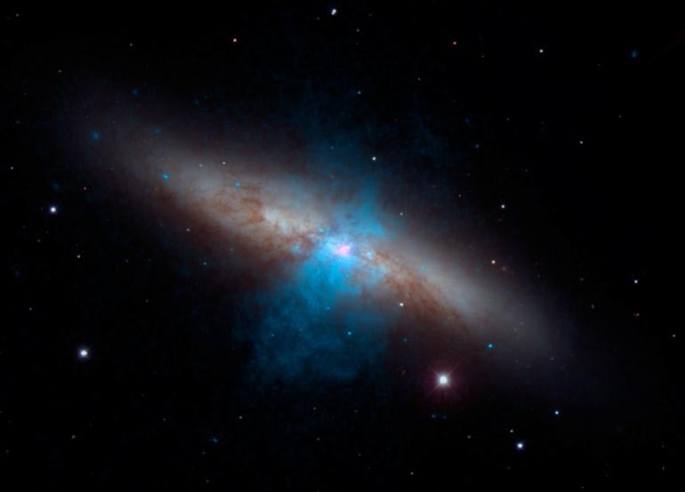 A shining dead star beaming with the power of 10 million suns was photographed by NASA's Nuclear Spectroscopic Telescrope Array (NuSTAR). This is the brightest pulsar ever recorded. The pulsar, a dense stellar remnant left over from a supernova explosion (pink), can be seen at the center of the galaxy Messier 82 in this new multi-wavelength portrait. NASA's NuSTAR mission discovered the "pulse" of the pulsar — a type of dead star — using high-energy X-ray vision.