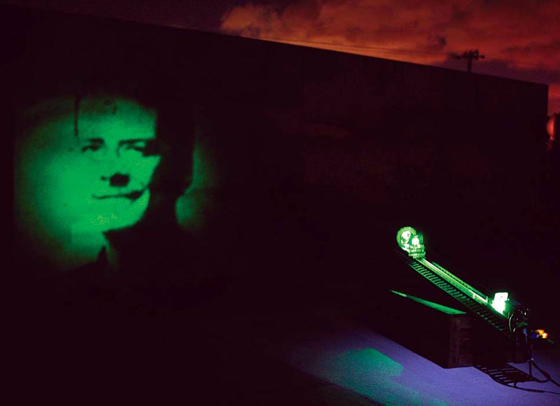 A green image of PopSci's editor-in-chief, Mark Jannot on a wall in front of a laser projector.