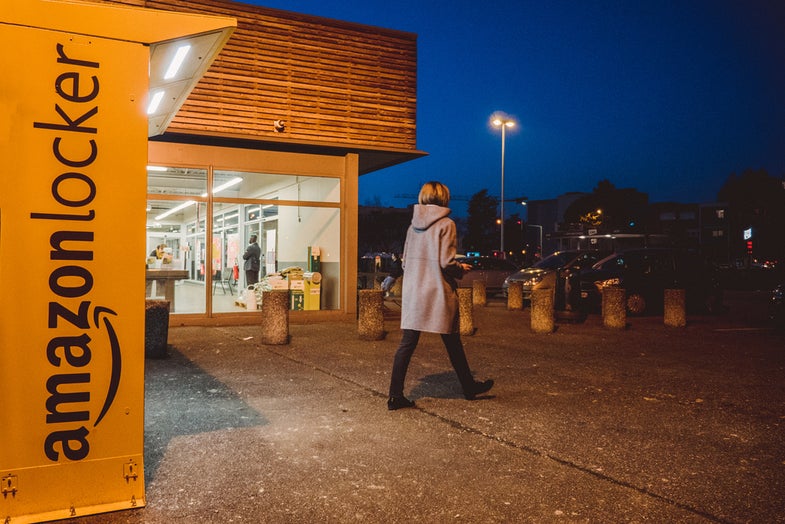 PARIS, FRANCE - FEB 15, 2017: Woman leaving Amazon locker orange delivery package locker at dusk - Amazon Locker is a self-service parcel delivery service offered by online retailer Amazon.com. Amazon customers can select any Locker location as their delivery address, and retrieve their orders