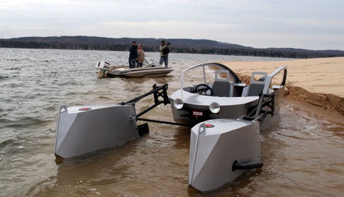 A homemade aluminum jet ski boat that looks like a Star Wars podracer, floating in shallow water near a beach.