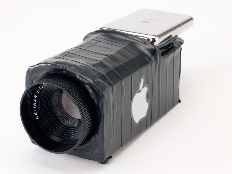 An iPod taped to a slide-projector lens to make a DIY video projector.