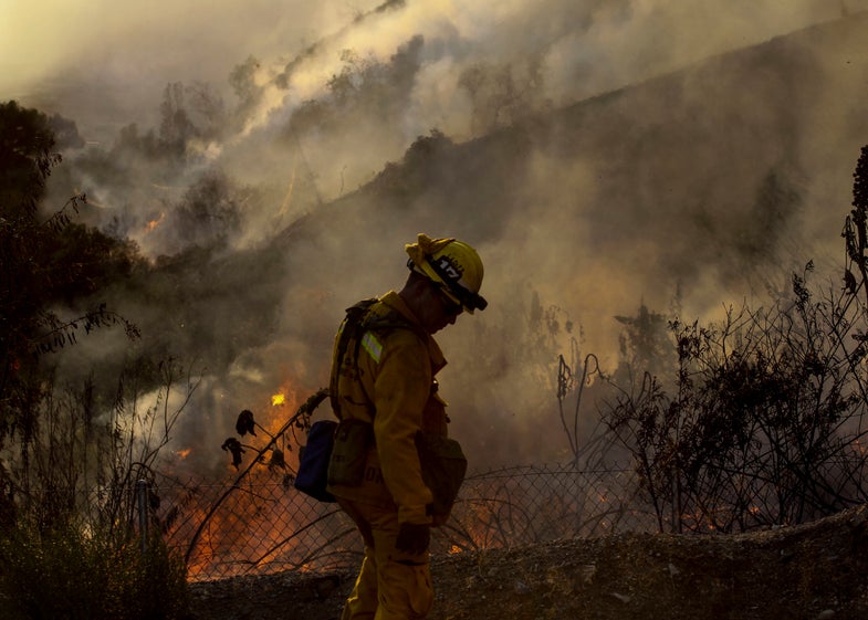 A firefighter keeps watch a wildfire along a hillside in Azusa, Calif., Monday, June 20, 2016. Police in the city of Azusa and parts of Duarte ordered hundreds of homes evacuated. Others were under voluntary evacuations. (AP Photo/Ringo H.W. Chiu)