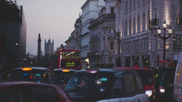 Cars and buses on busy London street at dusk.