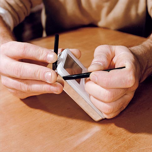 <em>Using a small flat tool, begin prying open the case. Then wedge the tool inside and use another to undo the case clips.</em>