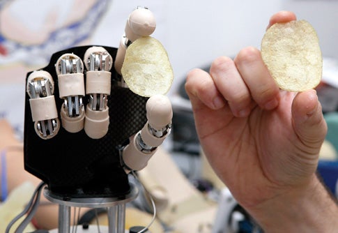 a human and a robotic hand holding chips