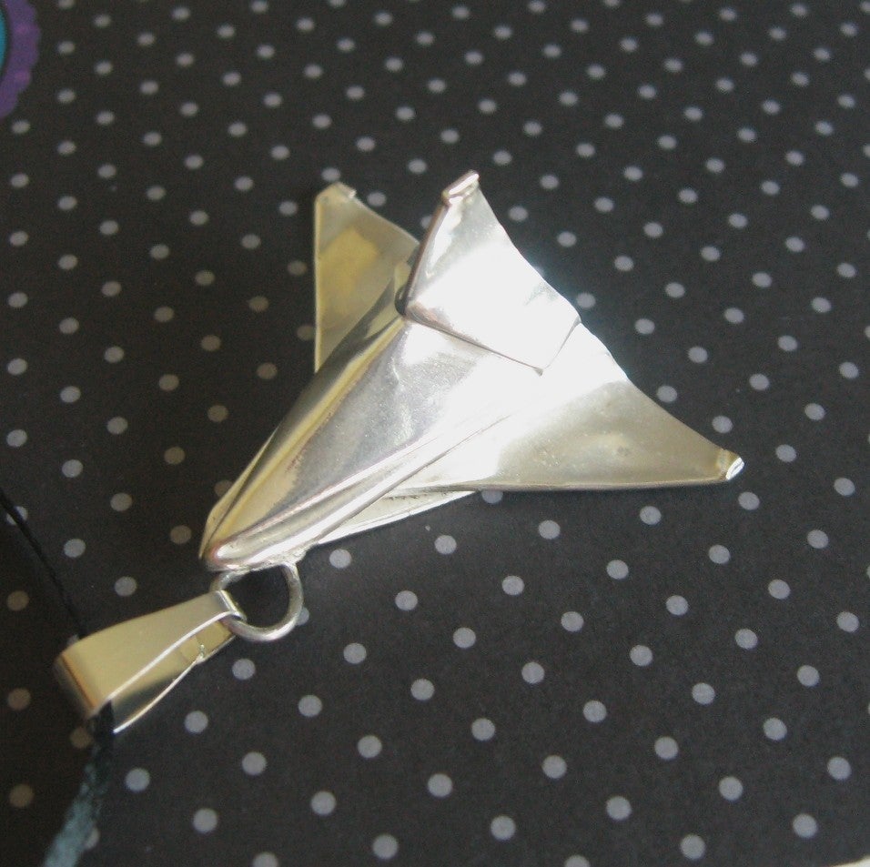 Despite the contest's broad scope, space shuttle-themed items were fairly common. This elegant pendant was a finalist in the 3-D category (it already sold). It's real origami, folded from a single piece of .999 fine silver with no cuts. It was kiln fired and polished before being attached to a ball for threading on a necklace.