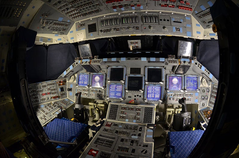 Commander's (left) and pilot's (right) seats aboard Atlantis' flight deck. In this and the following photographs, the forward windows have been covered and when not powered, some of the cockpit displays are protected by screen covers that replicate the data they show when lit.
