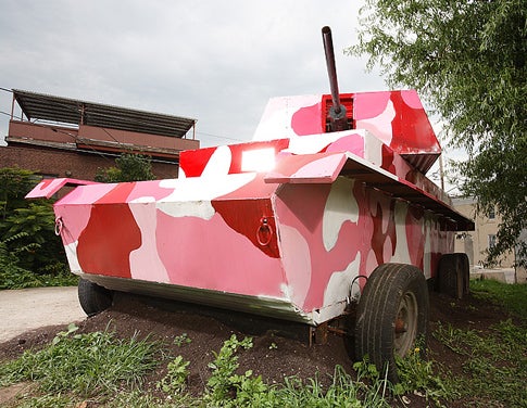 A pink camouflage patterned replica tank sitting in a yard.