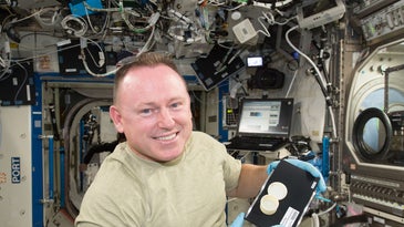 Astronaut Butch Wilmore holds a container that was 3D printed on the International Space Station.