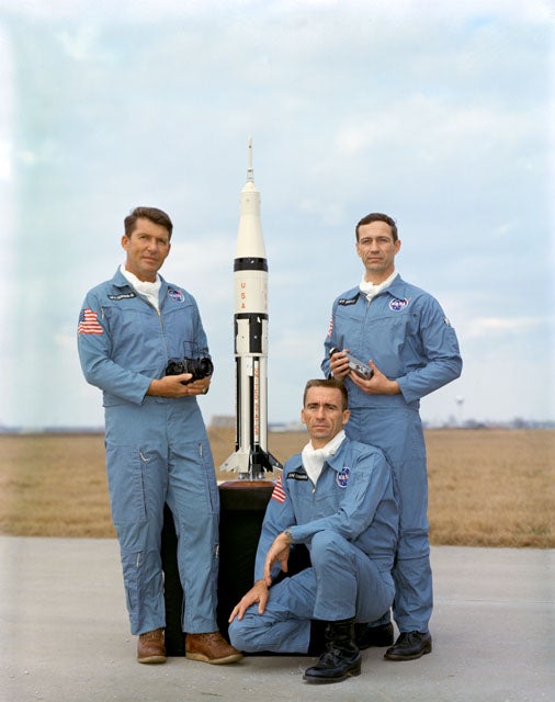 Apollo 7 crew posing with the model Saturn IB