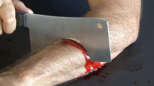 A Halloween costume with a plastic cleaver that looks to be embedded in a man's forearm, complete with fake blood.