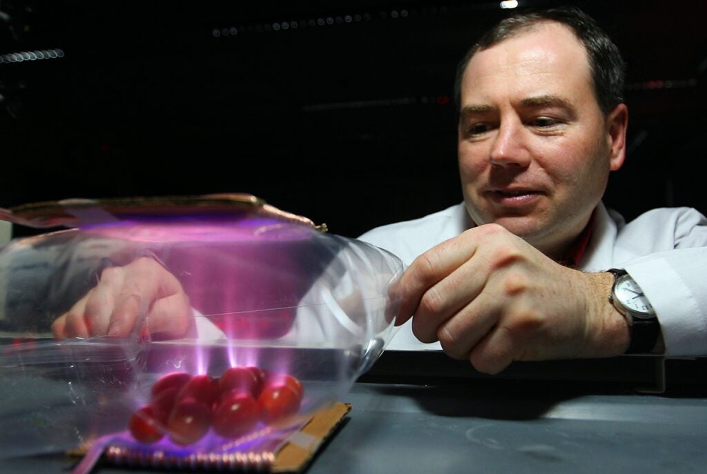 Kevin Keener's in-bag ozonation method uses high-voltage coils to charge the gas inside sealed food packages, effectively killing any bacteria inside them. In this demonstration with a bag of tomatoes, glowing helium shows the ionization process.