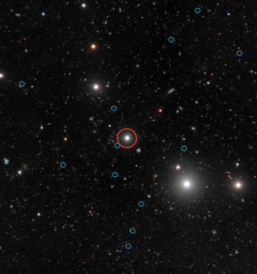 This deep image shows the region of the sky around the quasar HE0109-3518. The quasar is labelled with a red circle near the centre of the image. The energetic radiation of the quasar makes dark galaxies glow, helping astronomers to understand the obscure early stages of galaxy formation. The faint images of the glow from 12 dark galaxies are labelled with blue circles. Dark galaxies are essentially devoid of stars, therefore they don’t emit any light that telescopes can catch. This makes them virtually impossible to observe unless they are illuminated by an external light source like a background quasar.This image combines observations from the Very Large Telescope, tuned to detect the fluorescent emissions produced by the quasar illuminating the dark galaxies, with colour data from the Digitized Sky Survey 2.
