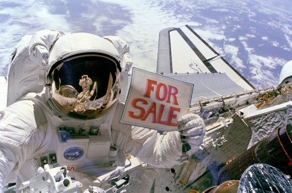Astronaut Dale Gardner holds up a "For Sale" sign, referring to two satellites, Palapa B-2 and Westar 6, that were retrieved from orbit.
