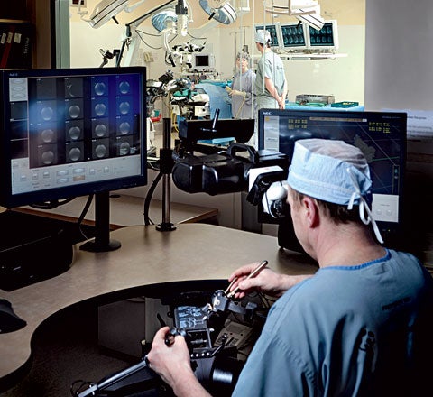 An array of monitors helps surgeons keep an eye on progress and reference pre-op scans as they use a joystick and stylus to control the neuroArm's robotic hands.