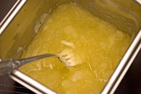 A sixth pan full of yellow citrus granita, with a fork in it for mixing.