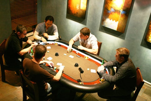A group of people playing poker in a room.
