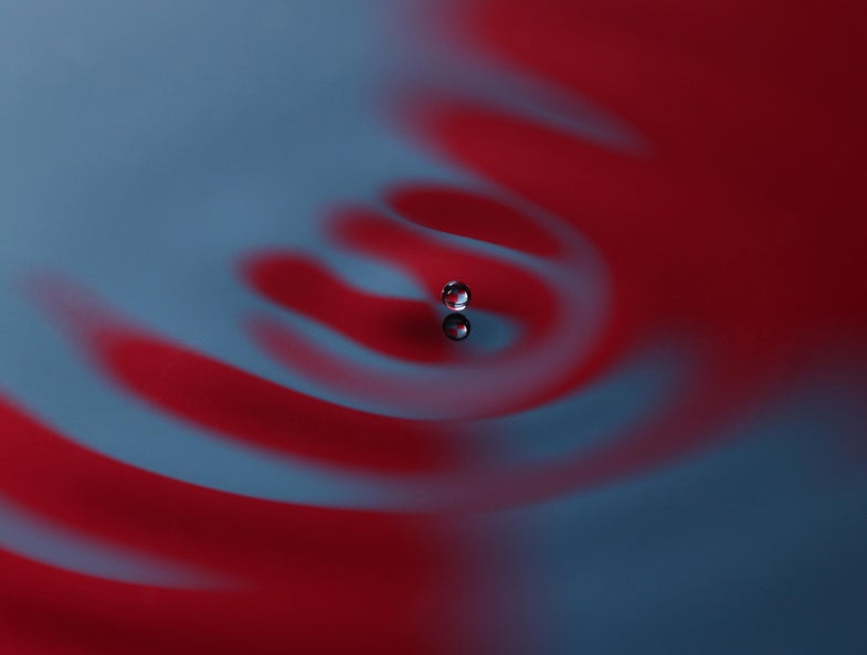 a droplet bounces across a red and blue water surface