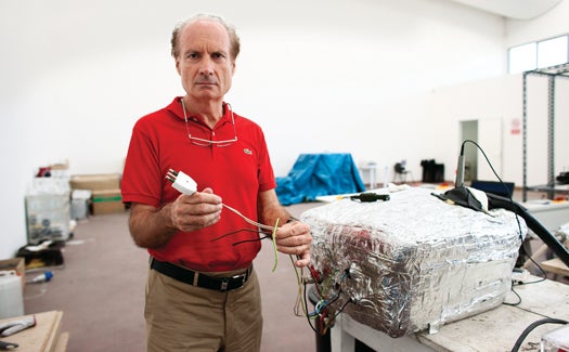 Rossi in his Bologna warehouse with a 10-kilowatt E-Cat module. He has been criticized in the past for not unplugging his machine during demos.