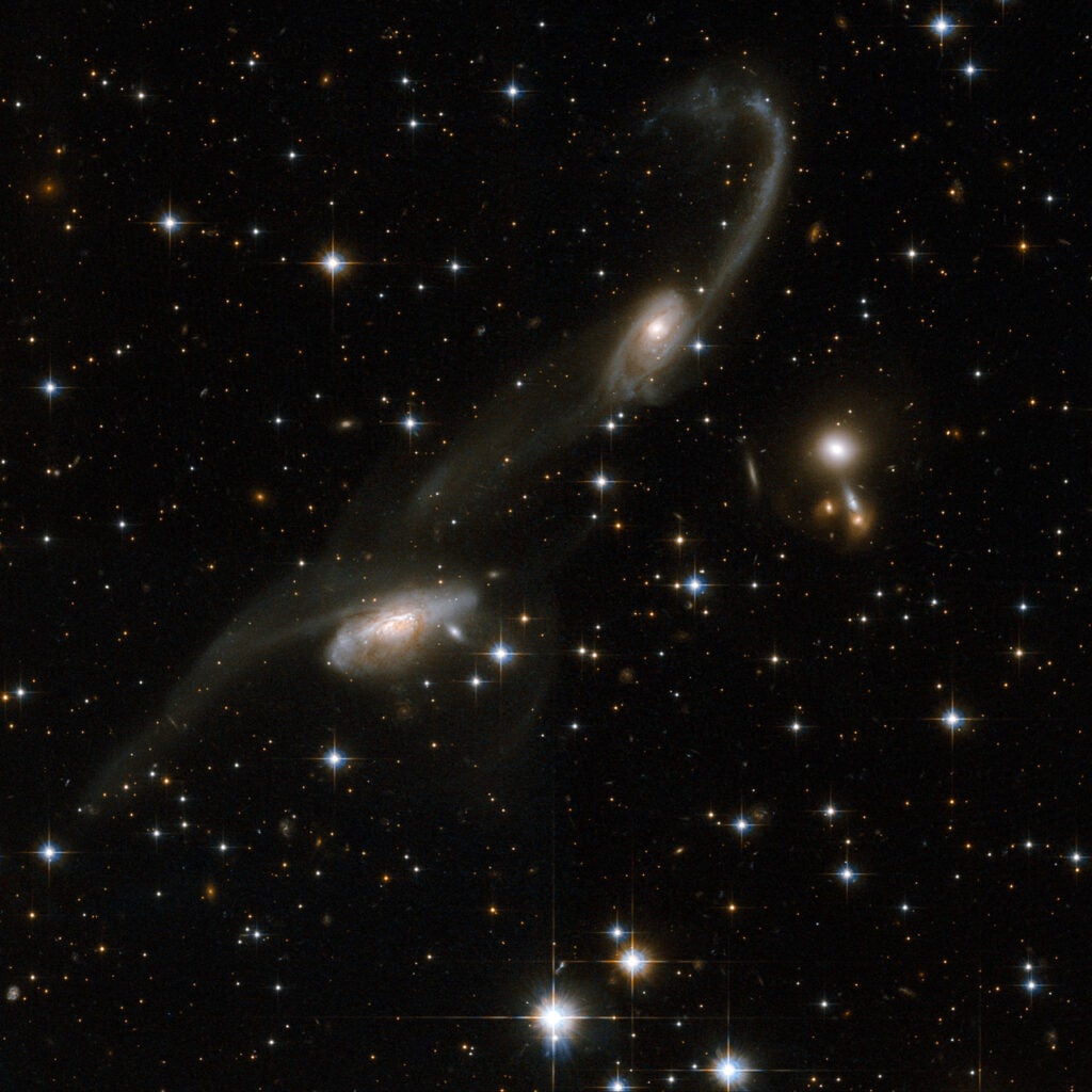 The galaxies of this beautiful interacting pair bear some resemblance to musical notes on a stave. Long tidal tails sweep out from the two galaxies: gas and stars were stripped out and torn away from the outer regions of the galaxies. The presence of these tails is the unique signature of an interaction. ESO 69-6 is located in the constellation of Triangulum Australe, the Southern Triangle, about 650 million light-years away from Earth.