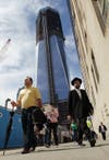 New Yorkers in downtown Manhattan walk through the construction zone, with One World Trade Center looming above.