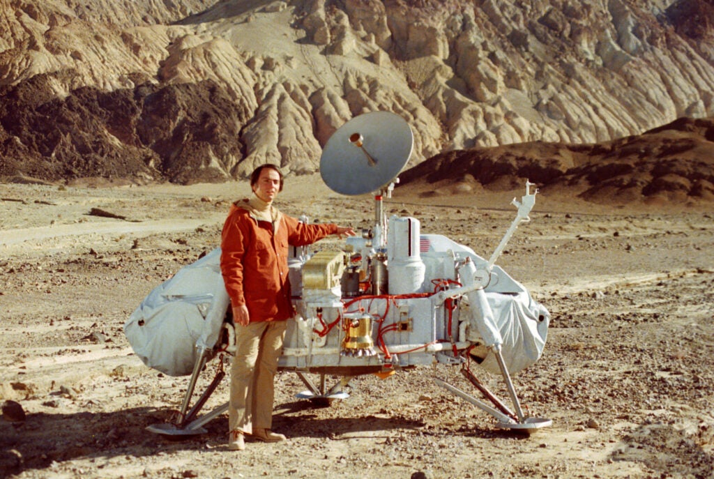 Carl Sagan stands next to Viking 1 model