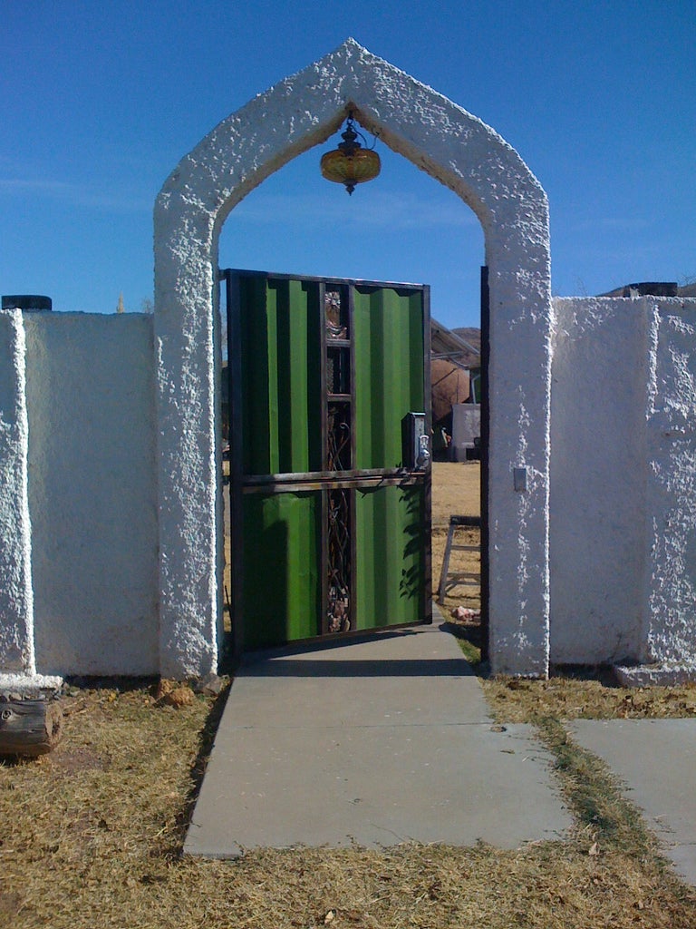 A fence gate with an archway made out of papercrete and painted with elastomeric paint.