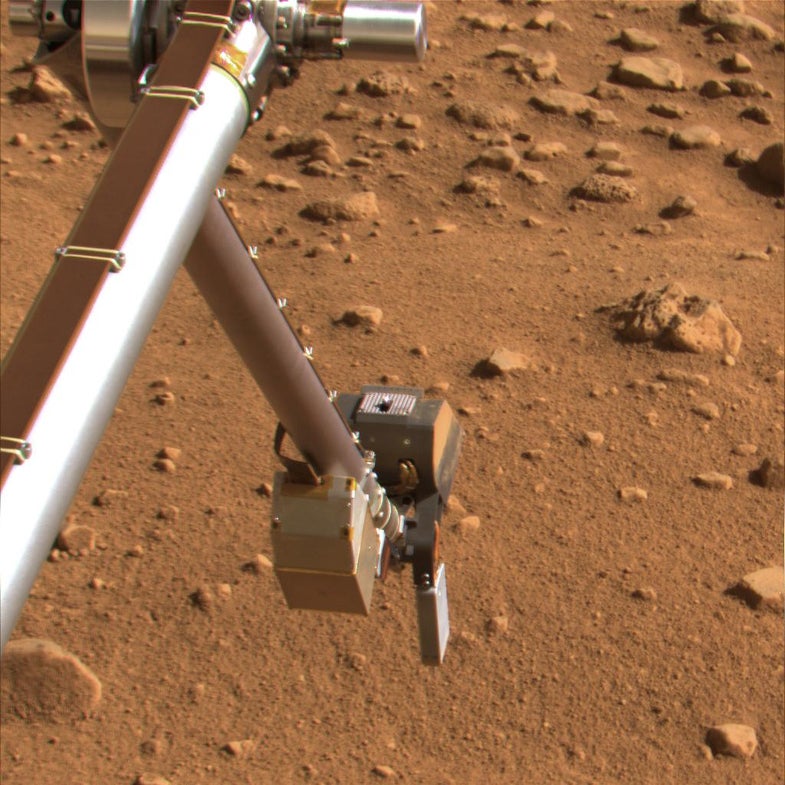 The Phoenix lander prepares to grate some Martian rocks.