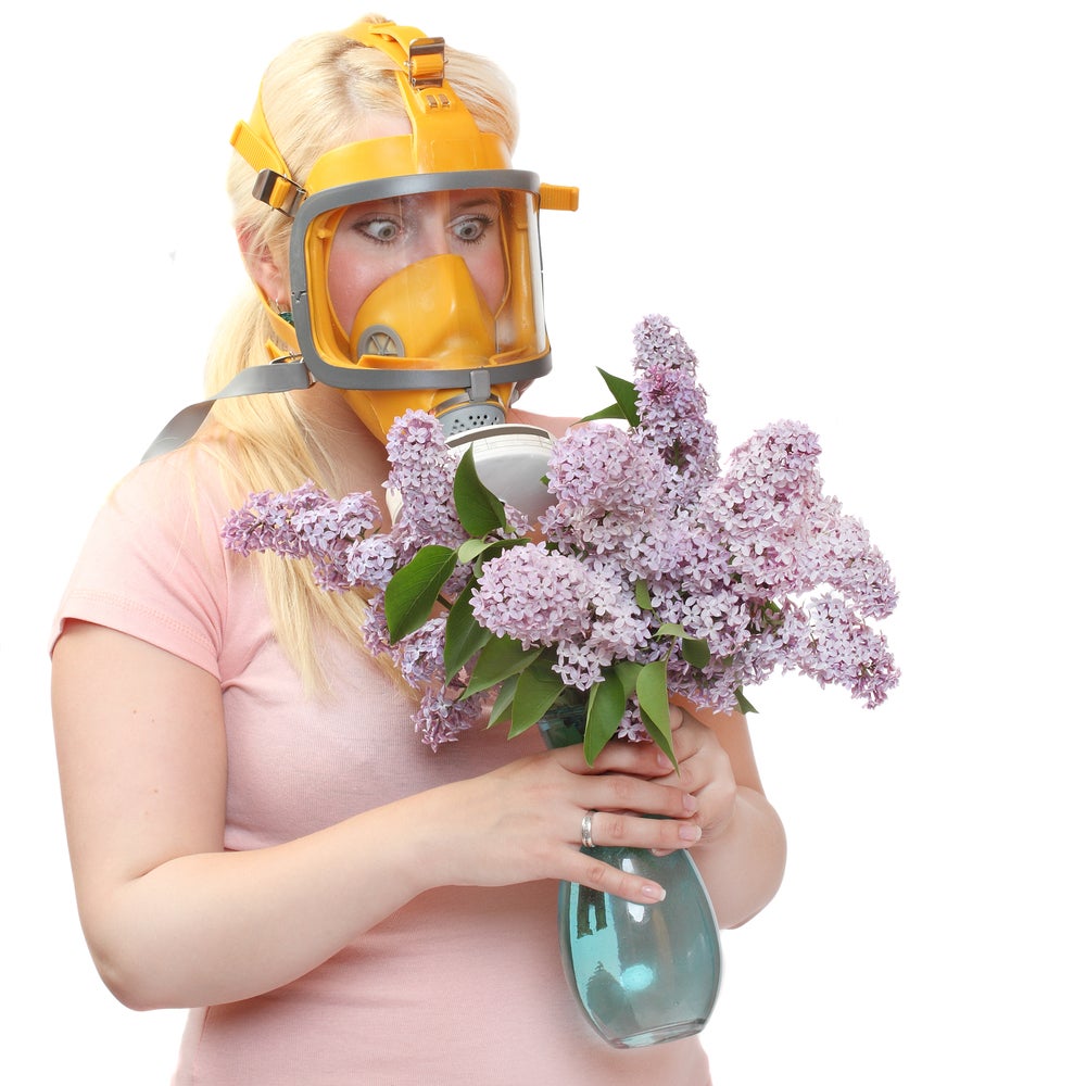 a woman holding flowers and wearing a gas mask