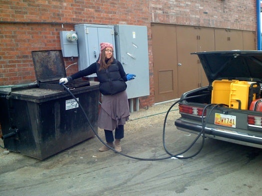 A woman pumping waste oil behind a gas station in Marfa, Texas, to use in a nearby Mercedes that runs on vegetable oil.